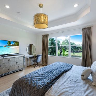 Bright bedroom with large window, elegant dresser, and cozy bed.