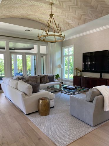 Bright living room with beige sofa, glass coffee table, and large TV.
