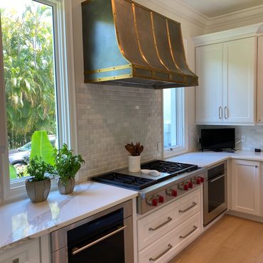 Modern kitchen with white cabinetry and brass-accented range hood.