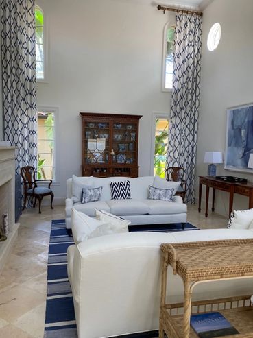 Elegant living room with white sofas, patterned curtains, and a wooden cabinet.