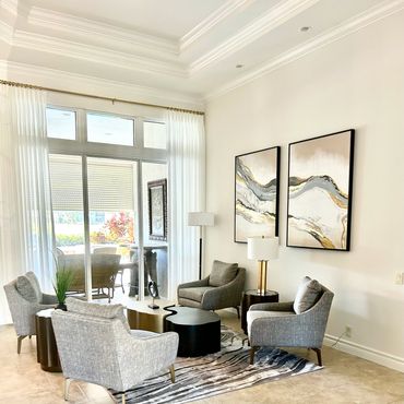 Modern living room with gray chairs, abstract wall art, and a stylish coffee table.