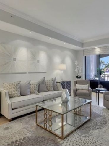 Modern living room with neutral tones and large windows overlooking greenery.