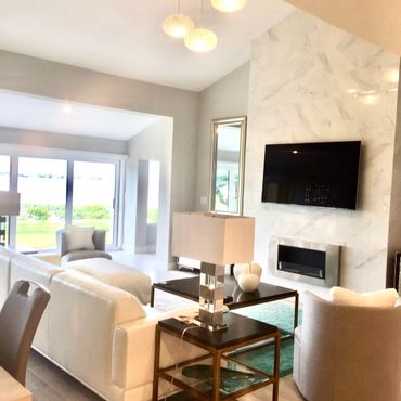Modern living room with white furniture and a wall-mounted TV above a sleek fireplace.