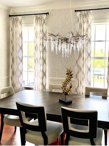 Elegant dining room with patterned curtains and crystal chandelier.