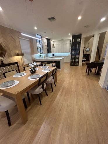 Modern open kitchen and dining area with wooden flooring and elegant decor.
