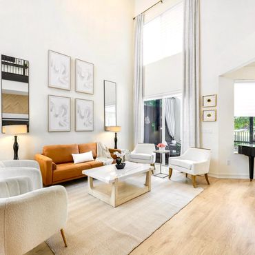 Bright modern living room with white chairs, orange sofa, and a grand piano.