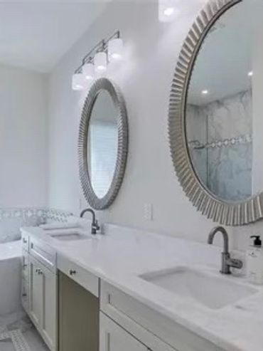 Modern bathroom with double sinks, round mirrors, and a freestanding bathtub.