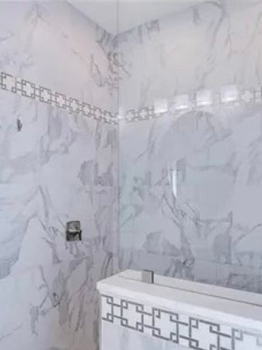 Modern bathroom with marble walls and a shower-bathtub combo.