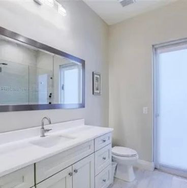 Bright modern bathroom with white cabinets and frosted glass door.