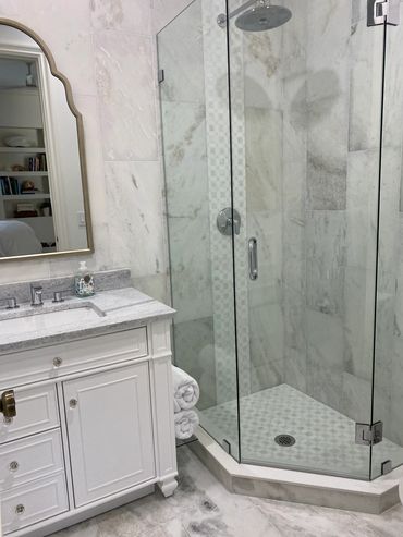 Modern bathroom with marble tiles and glass shower enclosure.