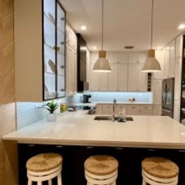 Modern kitchen with a white island and wicker stools.