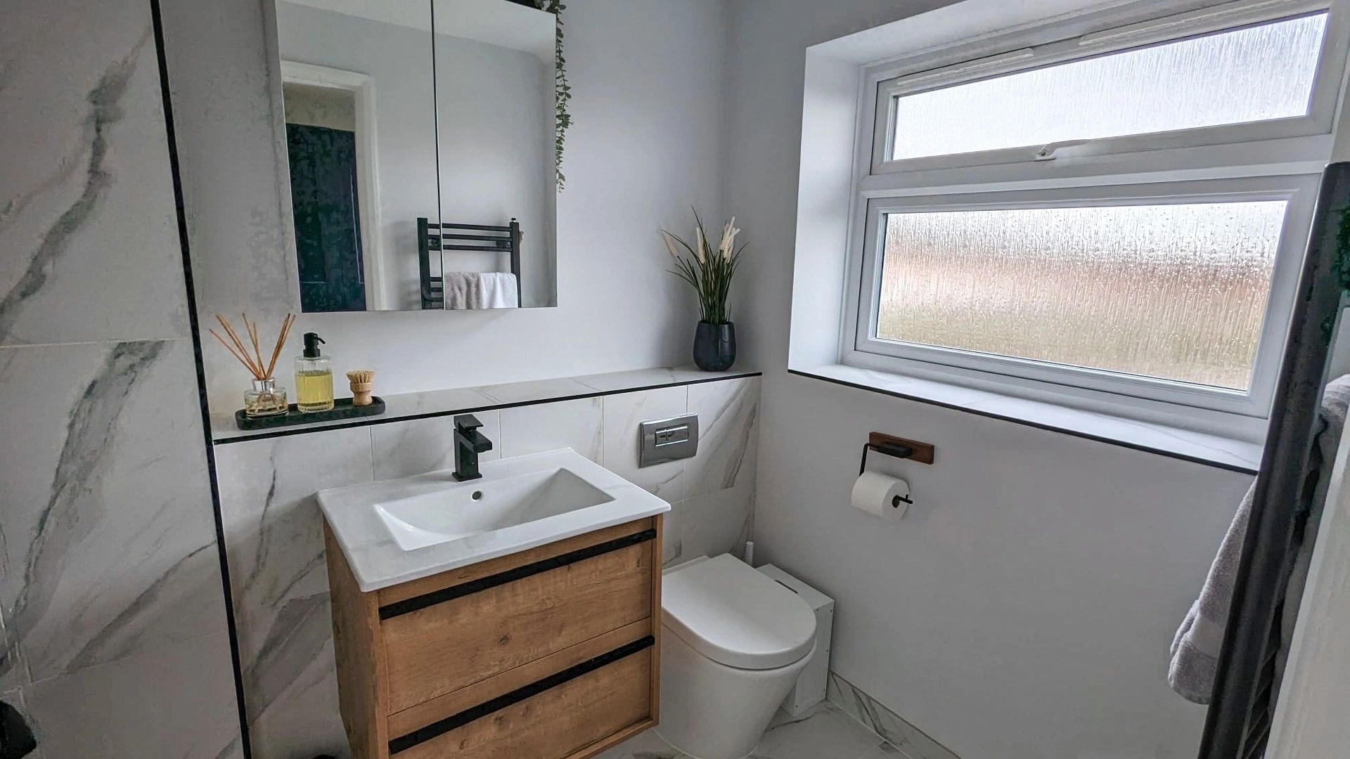 Ensuite with black fittings and marble style tiling.
