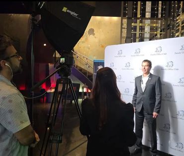 Man in suit being filmed in front of a Family Office Club backdrop.
