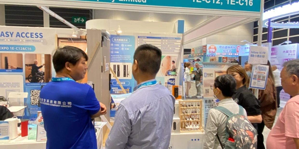People explore technology exhibits at a busy trade show booth.