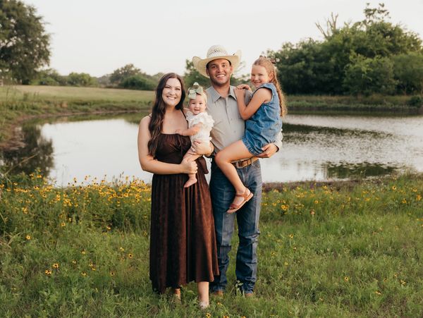 Happy family of four by a lake in a grassy field.