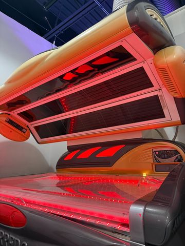 A modern tanning bed glowing with red LED lights in a sleek room.