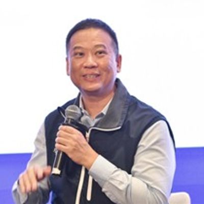 Man holding a microphone speaking at an event.