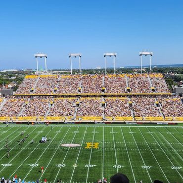 A sunny day football game with a packed stadium and clear blue sky.