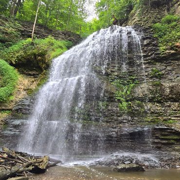 A large waterfall cascading over rocky cliffs surrounded by lush greenery.