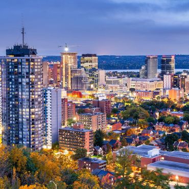 Evening cityscape with illuminated buildings and autumn trees.
