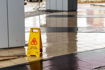 Yellow caution sign warns of wet floor on shiny tiled surface.