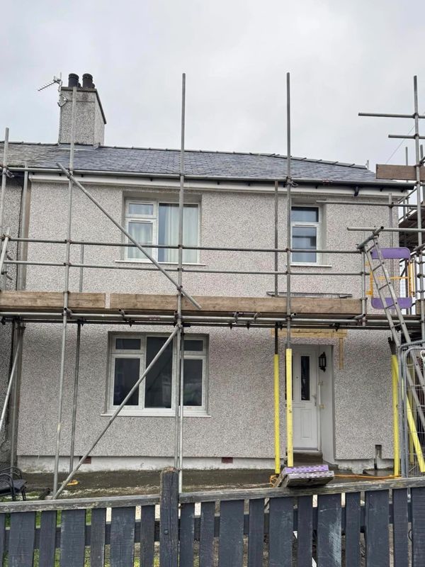 Two-story house under renovation with scaffolding on the front.