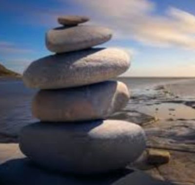 Balanced stack of smooth stones on a beach with a serene ocean backdrop.