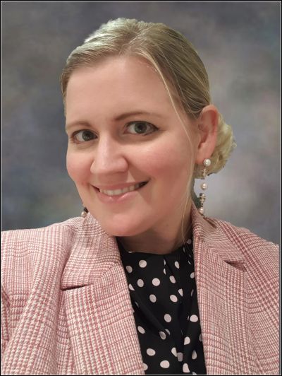 Woman smiling with a checkered blazer and polka dot top.