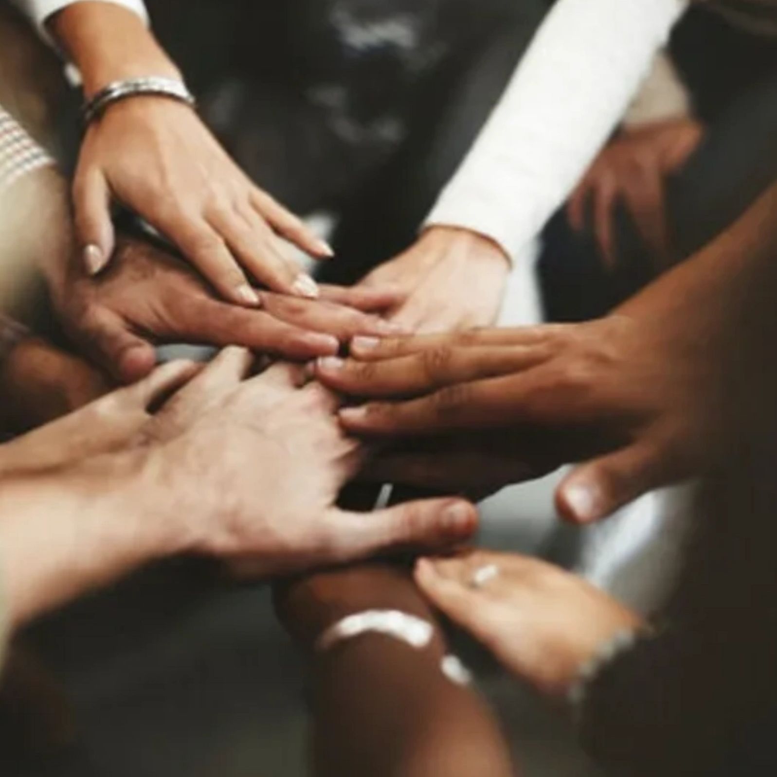 Diverse hands stacked together symbolizing unity and teamwork.