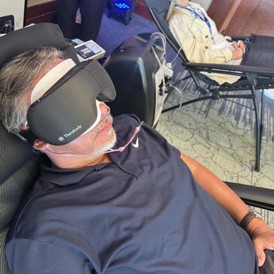 Two people relaxing with Therabody eye masks in reclining chairs.