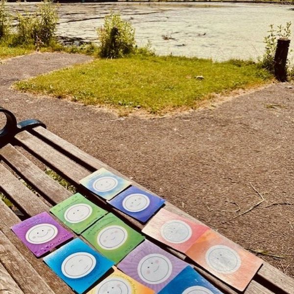 Colorful smiley face cards laid out on a park bench.
