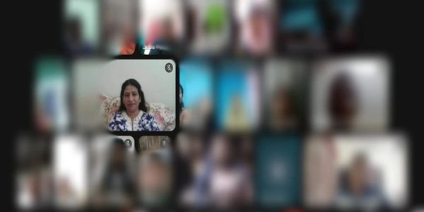 A woman appears in a highlighted video call screen among many blurred participants.