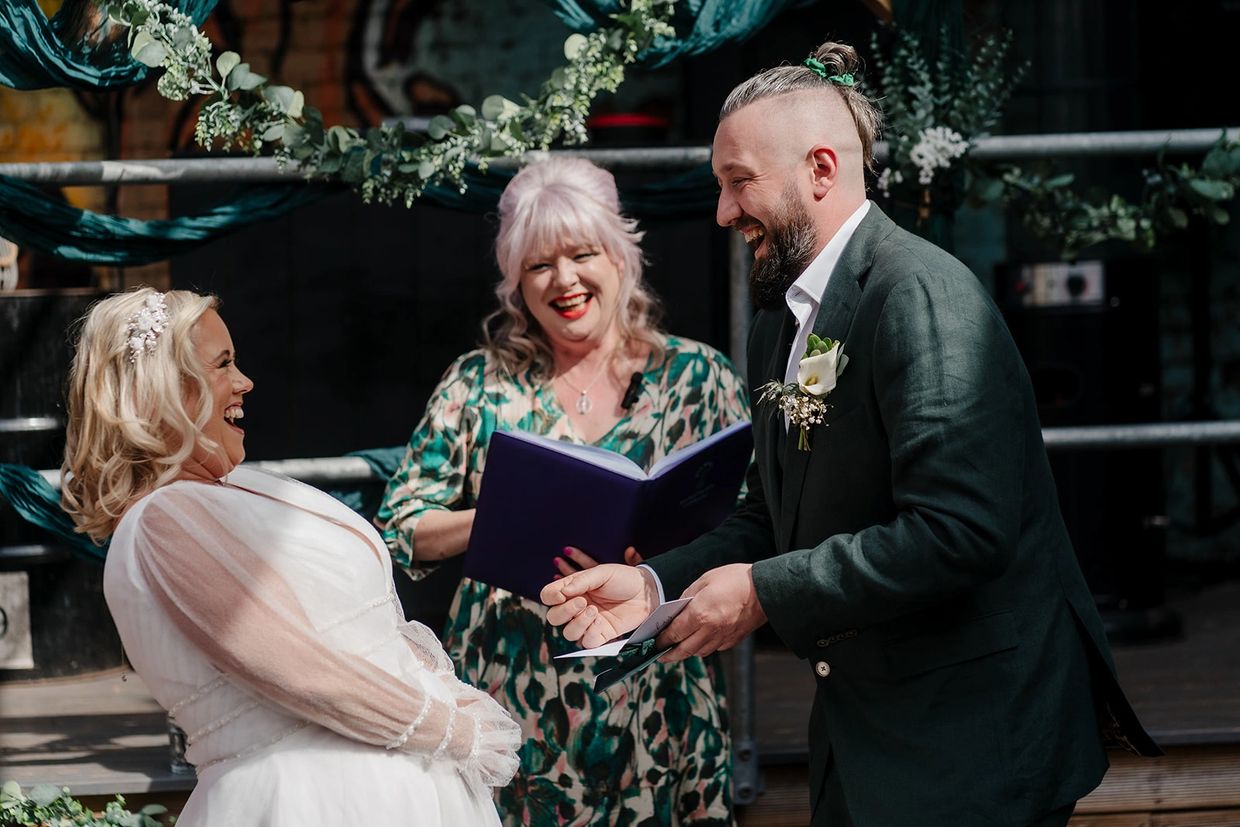 A joyful couple laughing with the celebrant during their wedding ceremony.