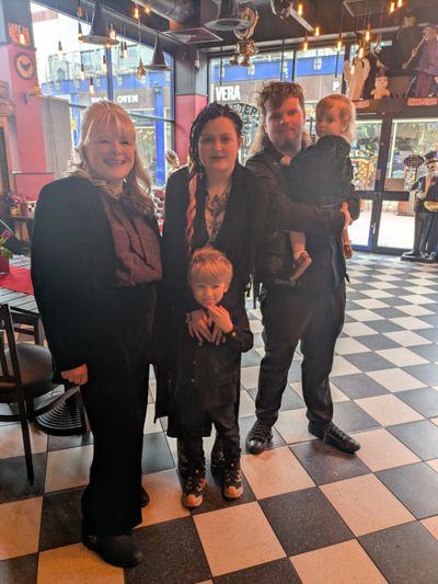 A smiling family of four in a cozy, decorated cafe with Halloween-themed decor.