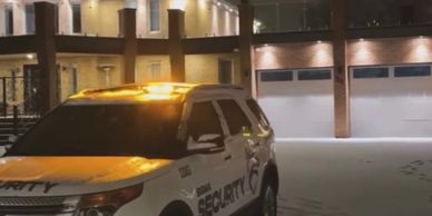 Security vehicle with lights on at night outside a building.