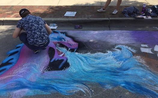 Artist painting a vibrant dragon with flowing blue water on pavement.