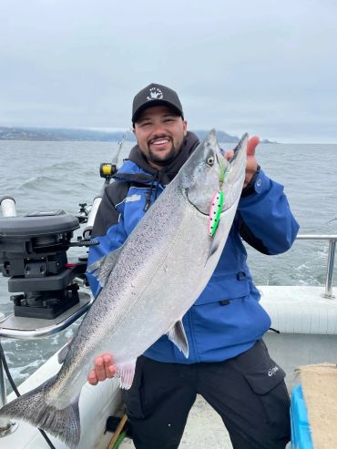 Man holds a large fish on a boat, smiling.