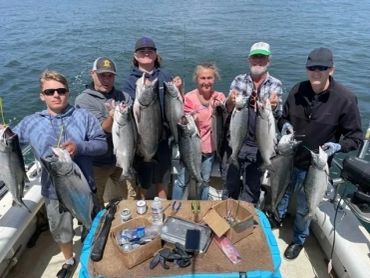 Group of six people on a boat showing off their large fish catch.