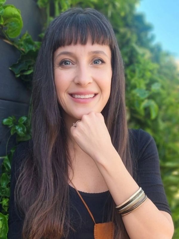 Smiling woman with long hair posing outdoors.