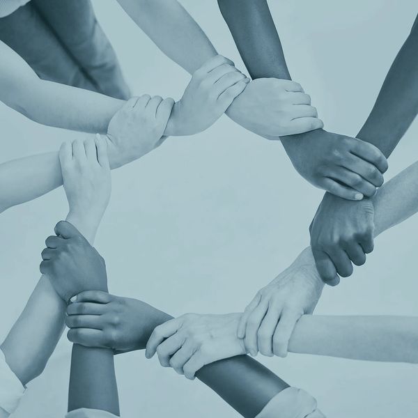 multiple ethnicities of hands overlapping each other to form a circle