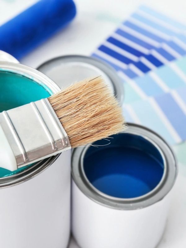 Cans of paint with brush on table, closeup