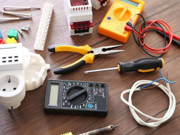 Different electrical tools on wooden table, top view