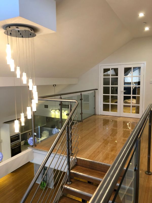 Modern staircase with glass railing and hanging pendant lights.