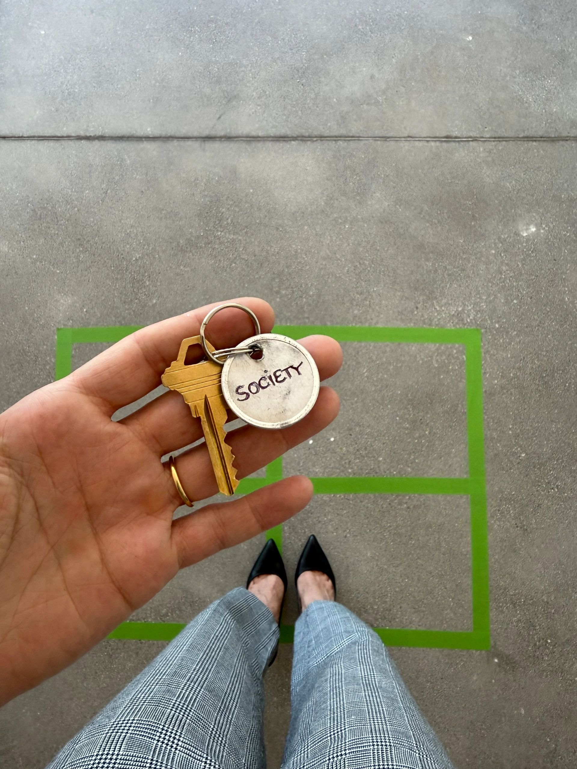 Hand holding keys with a tag labeled 'Society'.