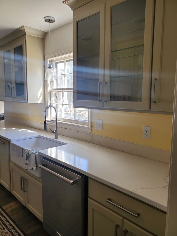 glass front kitchen cabinets and yellow walls and white quartz countertops