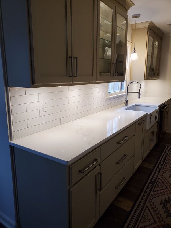 glass front kitchen cabinets and white subway tile backsplash and white quartz countertops