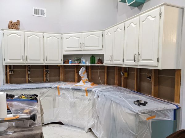 kitchen cabinets covered with plastic and studs exposed