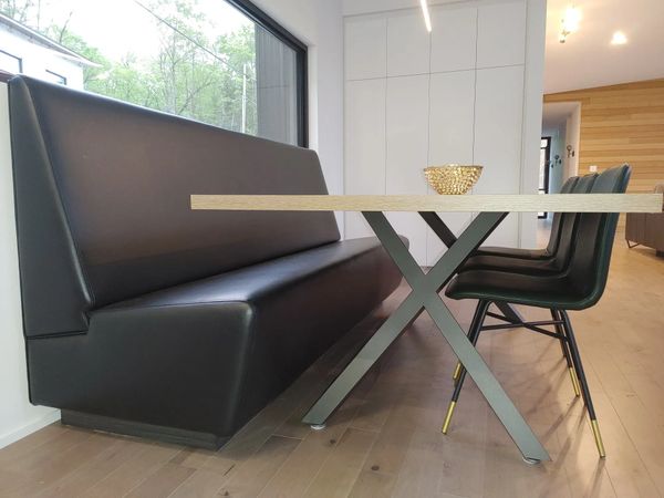 Modern dining area with black leather seating and a wooden table.