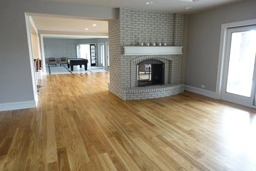 Spacious living room with wooden floors and a white brick fireplace.