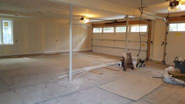Empty garage with construction materials and tools scattered on the floor.